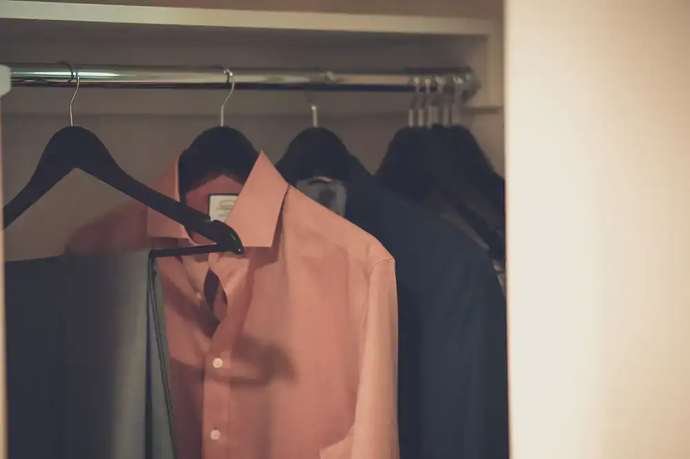 Freshly pressed white shirts hanging neatly on wooden hangers in a bright room